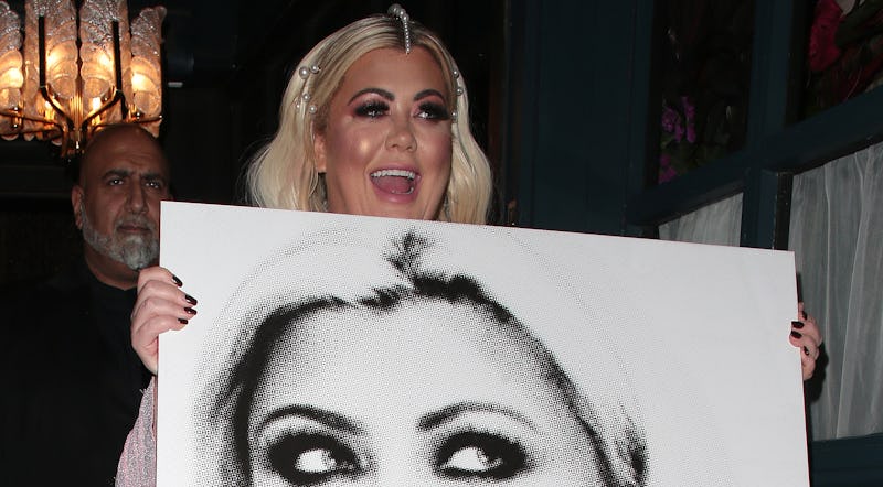 A blonde woman smiling while holding a large photo of herself she received as a Christmas gift.