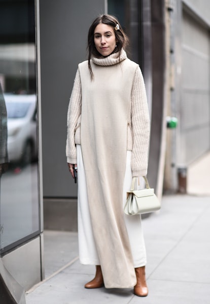 Street style photo of Lauren Caruso wearing a beige turtleneck and skirt under a long sweater tunic ...