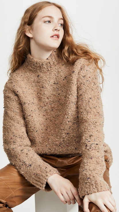 A redhaired model posing in a Slub Knit Sweater by GANNI