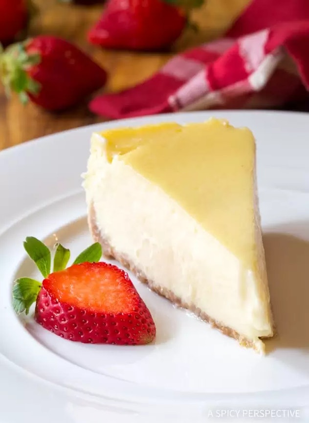 Thanksgiving Desserts: A slice of cheesecake on a plate with a slice of strawberry on the side