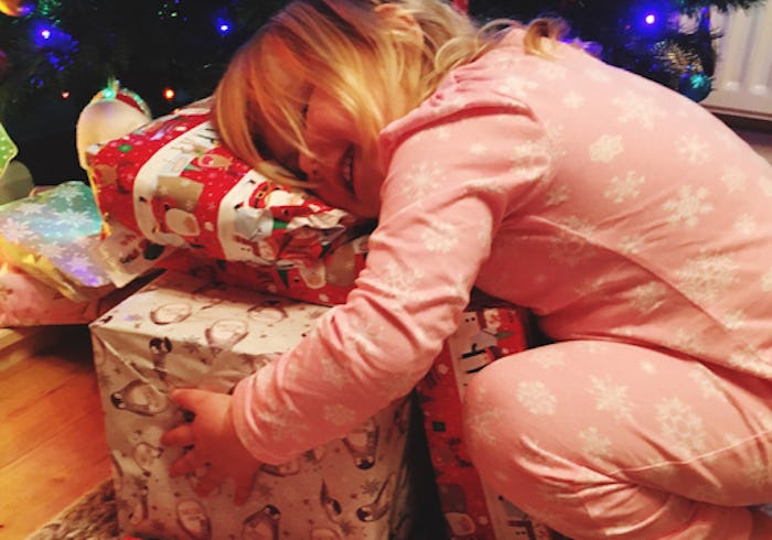 best holiday gifts for toddlers; toddler hugging a stack of wrapped holiday presents