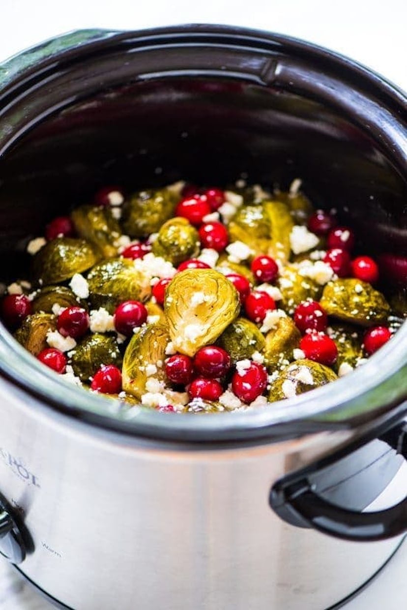 close up of green brussels sprouts with feta cheese and cranberries in slow cooker 