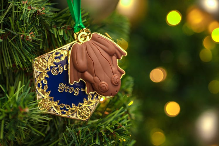 The chocolate frog ornament hangs on a Christmas tree.