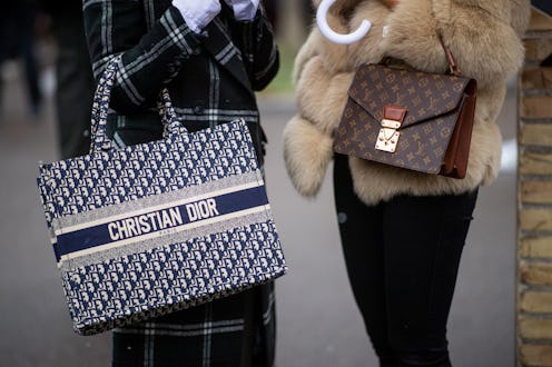 Two women standing outside in the winter both of them are holding designer handbags
