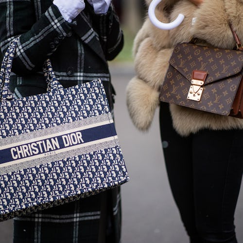 Two women standing outside in the winter both of them are holding designer handbags