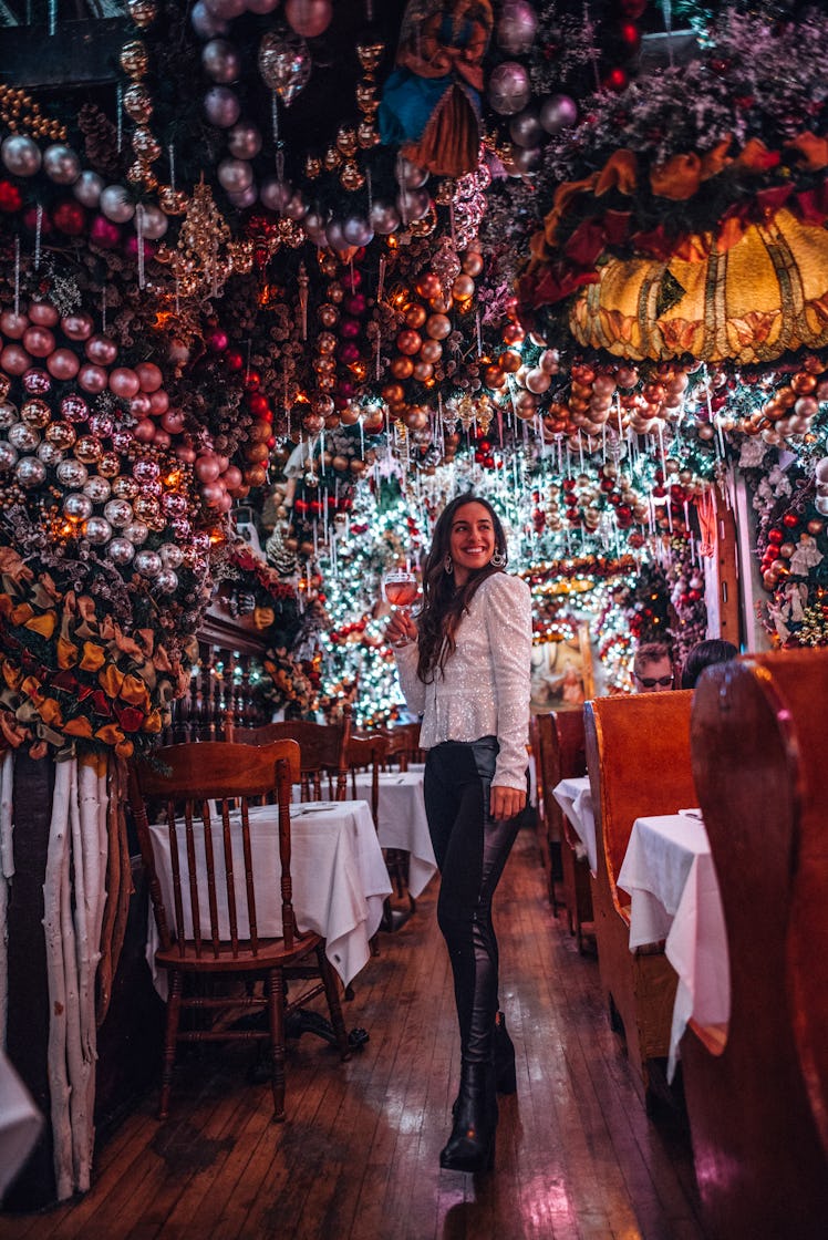 A travel blogger poses in Rolf's in New York City with a drink during the holidays.