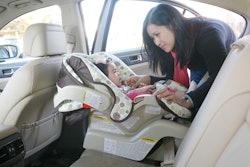 a mom buckling her baby into a car seat