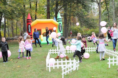 Children play with balloons in front of a jumping castle