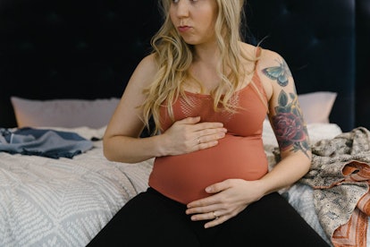How to make your baby drop and engage, pregnant woman sitting on the bed cradling her stomach