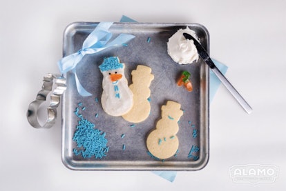 Snowman-shaped cookies, blue sprinkles, and blue ribbon on a metal tray at Alamo Drafthouse's 'Froze...