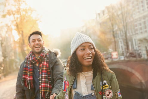 A young couple walks hand in hand down the street. 