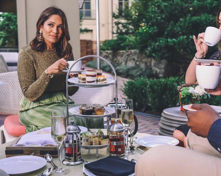 A stylish woman enjoys holiday afternoon tea and food with friends at Waldorf Astoria Atlanta Buckhe...