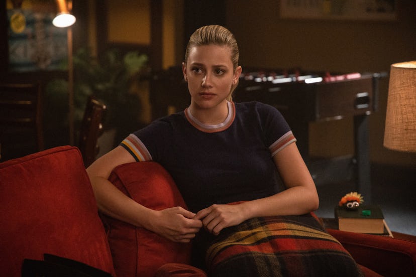 Betty sitting on a couch in Riverdale looking worried