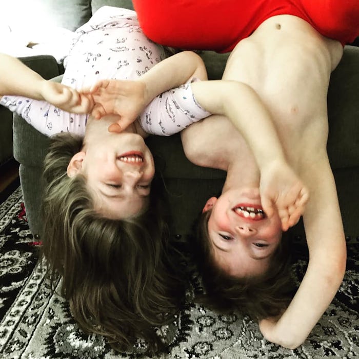 A picture of the author's children, smiling and hanging upside down from their couch.