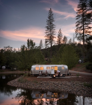 A group of friends hangs out near an AutoCamp airstream trailer at sunset.