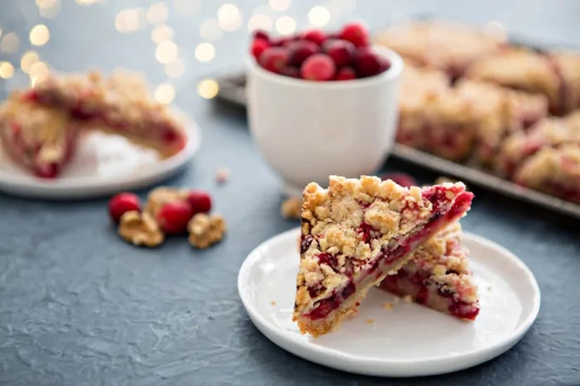 Thanksgiving sheet pan dessert, cranberry pomegranate walnut bar slices on a white plate with a seco...