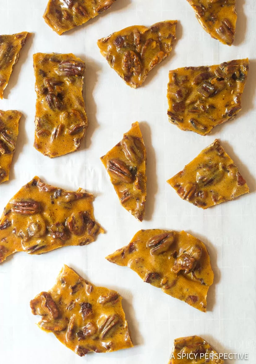 Thanksgiving sheet pan desserts, bacon pecan brittle in pieces scatted across a piece of parchment p...