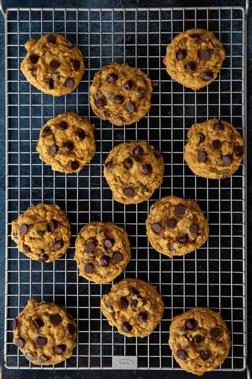 Thanksgiving sheet pan desserts, oatmeal pumpkin chocolate chip cookies sitting on a cooling rack wi...