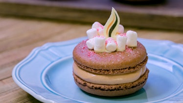 The hot cocoa marshmallow macaron has a white chocolate flame and marshmallows on top, and is offere...