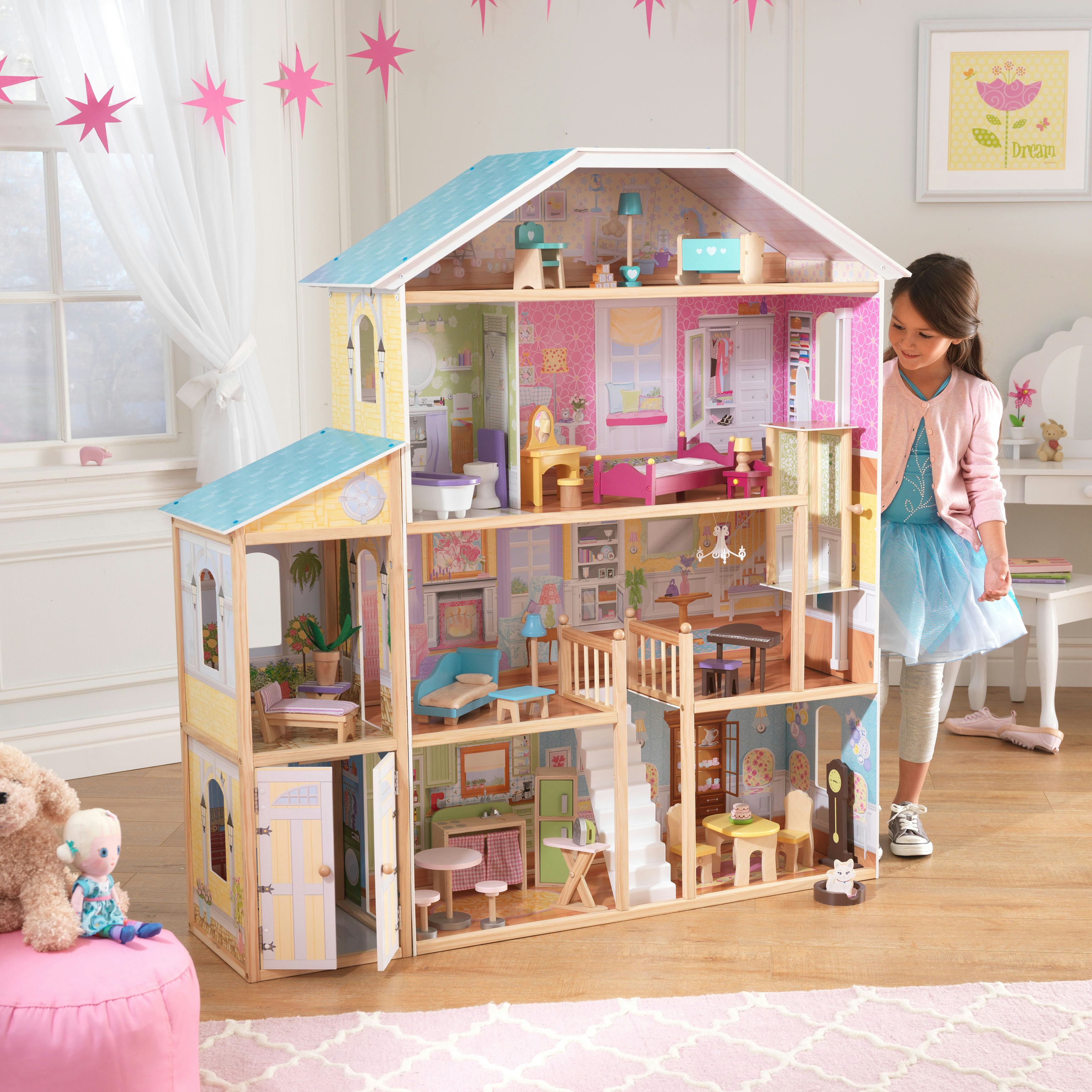 Little girl standing next to KidKraft Majestic Mansion Dollhouse