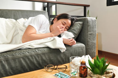 A woman with the flu lies on the couch.Vitamin c works to prevent the flu in a variety of ways.