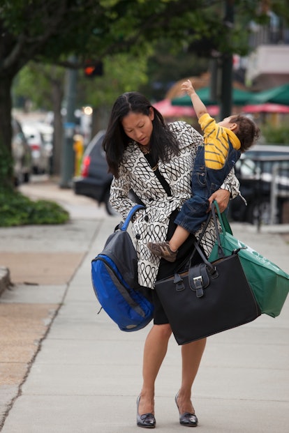 A mother struggles with carrying bags and her child.