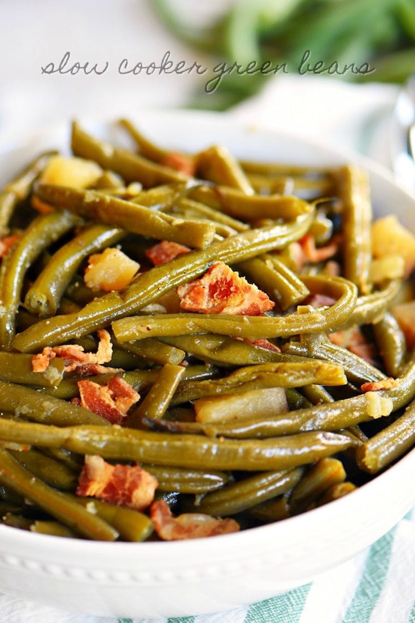 close up shot of green beans with chunks of bacon in a white bowl