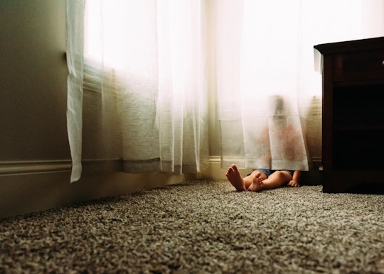 Child hides behind a curtain