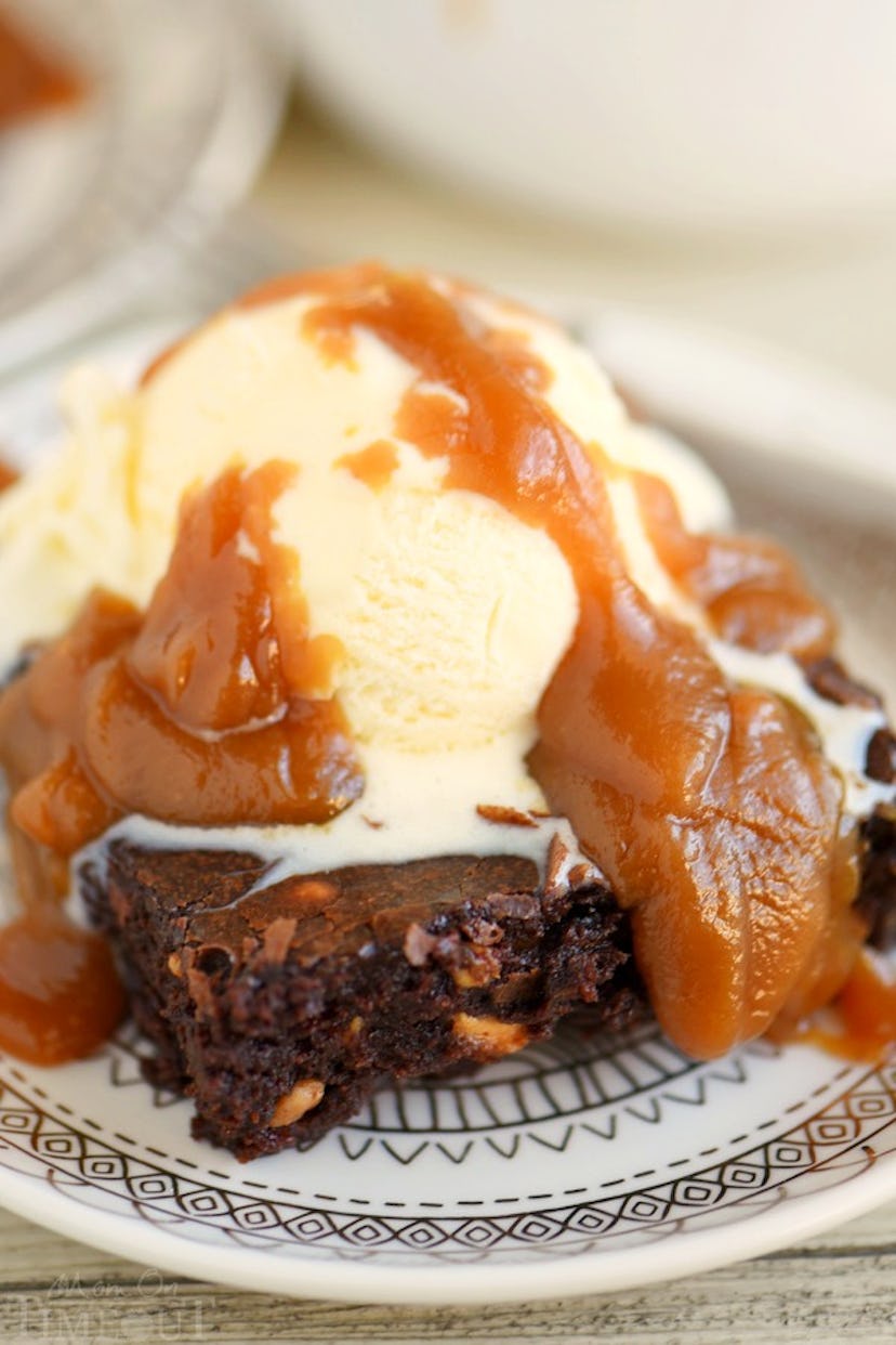 A soft brownie on a plate with vanilla ice cream and peanut butter sauce dripped over