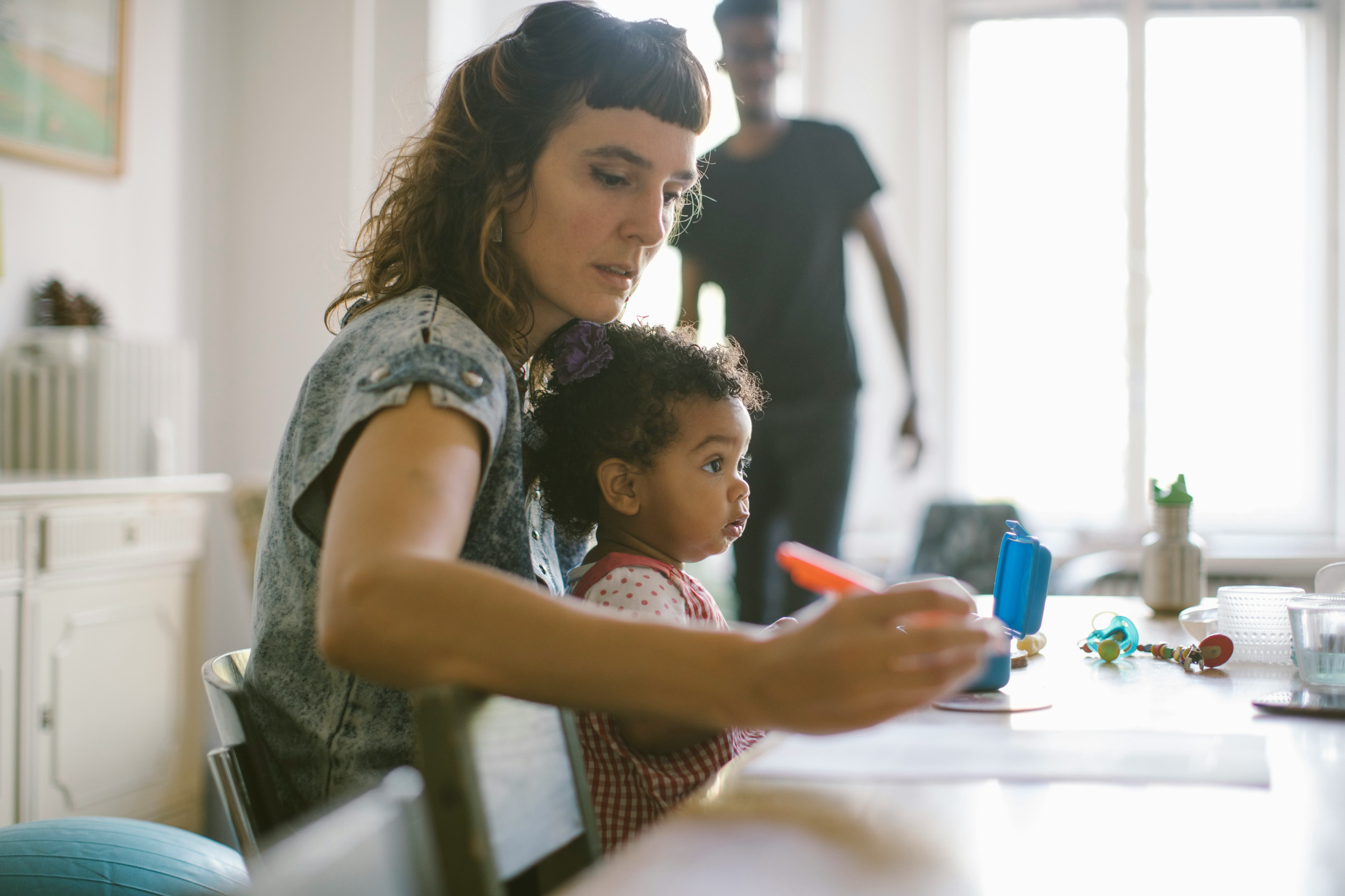 a mother works while toddler sits in her lap