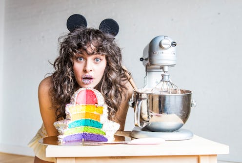 Amirah Kassem of Flour Shop poses with one of her signature rainbow cakes and a kitchenaid mixer.
