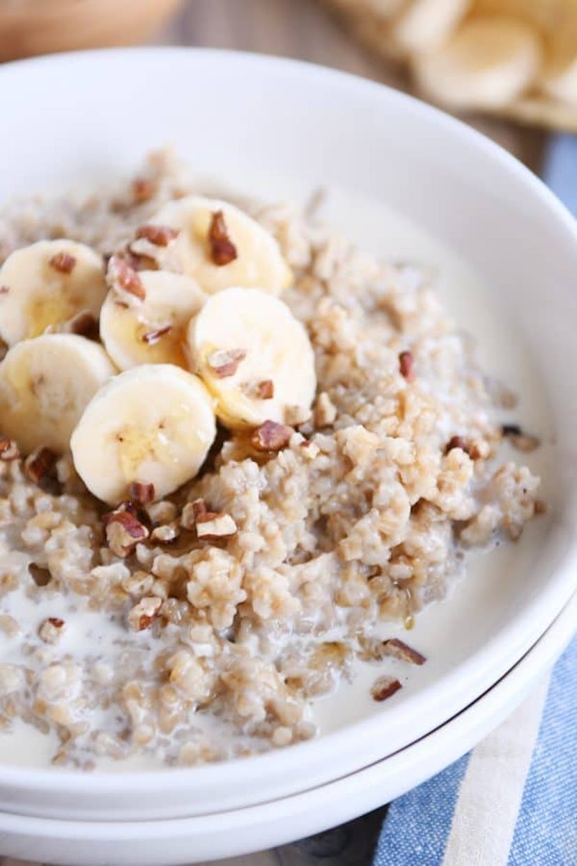 close up of bowl with oatmeal topped with crushed walnuts and sliced bananas