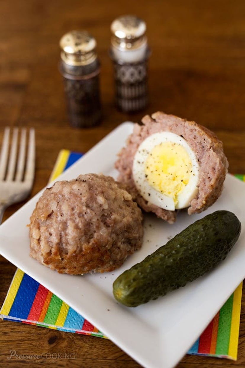 scotch egg cut in have with a side of pickle