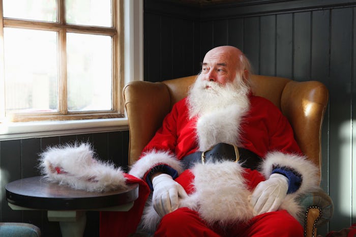 Santa sits looking out window with hat off