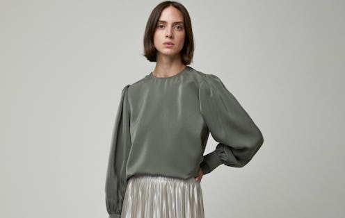 A model wearing Oak + Fort's pleated skirt and an olive-green blouse.