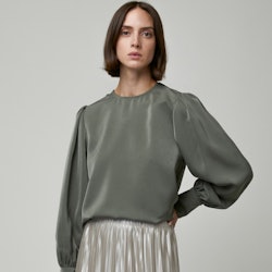 A model wearing Oak + Fort's pleated skirt and an olive-green blouse.