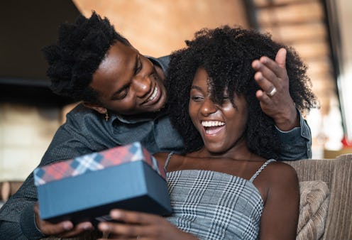Boyfriend surprising his excited girlfriend with a Christmas gift.