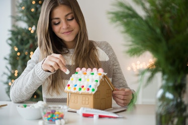 Young woman building gingerbread house.
