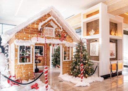 A life-size gingerbread cocktail bar is surrounded by fake snow, Christmas trees, and festive decor ...