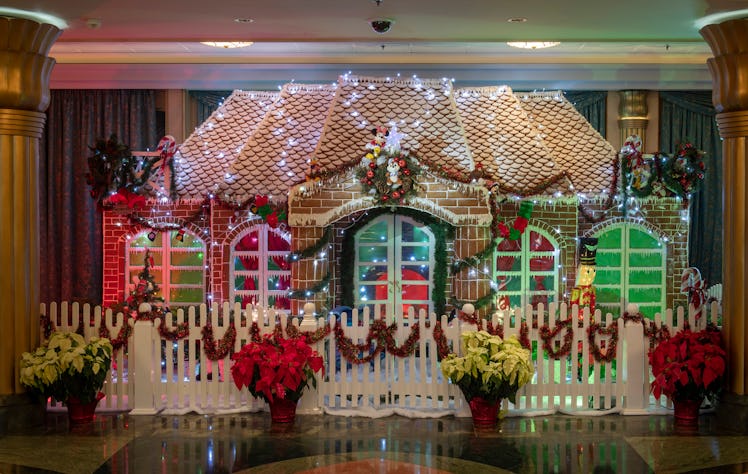 A giant gingerbread house with poinsettias surrounding it is on display on the Disney Cruise Line du...
