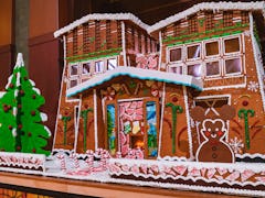 A giant gingerbread house with a Mickey gingerbread and Christmas tree in front is on display at Dis...