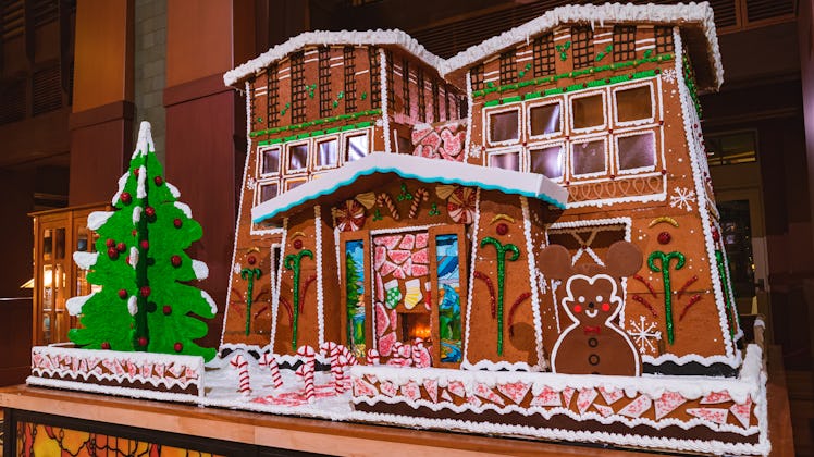 A giant gingerbread house with a Mickey gingerbread and Christmas tree in front is on display at Dis...