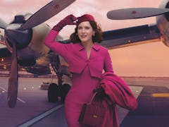 'The Marvelous Mrs. Maisel' Rachel Brosnahan stands on an airplane runway dressed in pink.