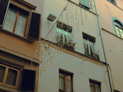 A set of twinkly lights hang over a street in Florence around Christmas.