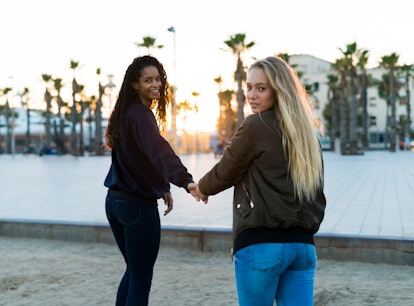 Two young women holding hands at sunset, showing the meaning of twin flame.