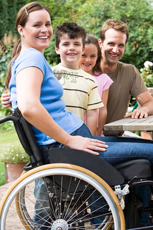 A mom in a wheelchair smiles with her children and partner