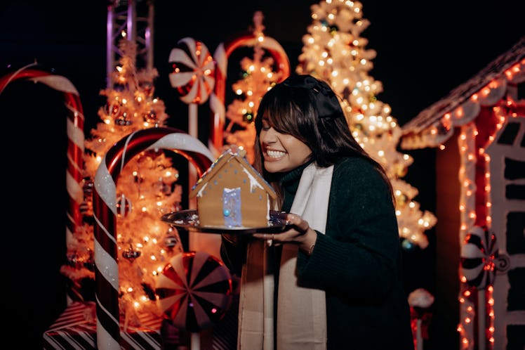 A woman smiles at her gingerbread house that she made at Santa's North Pole Village in LA. 