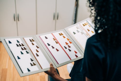 Woman choosing hair color in dye catalog. A new study suggests hair dye and relaxing was linked to b...