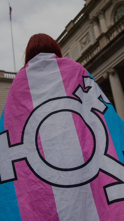 A woman wearing a trans flag on her back