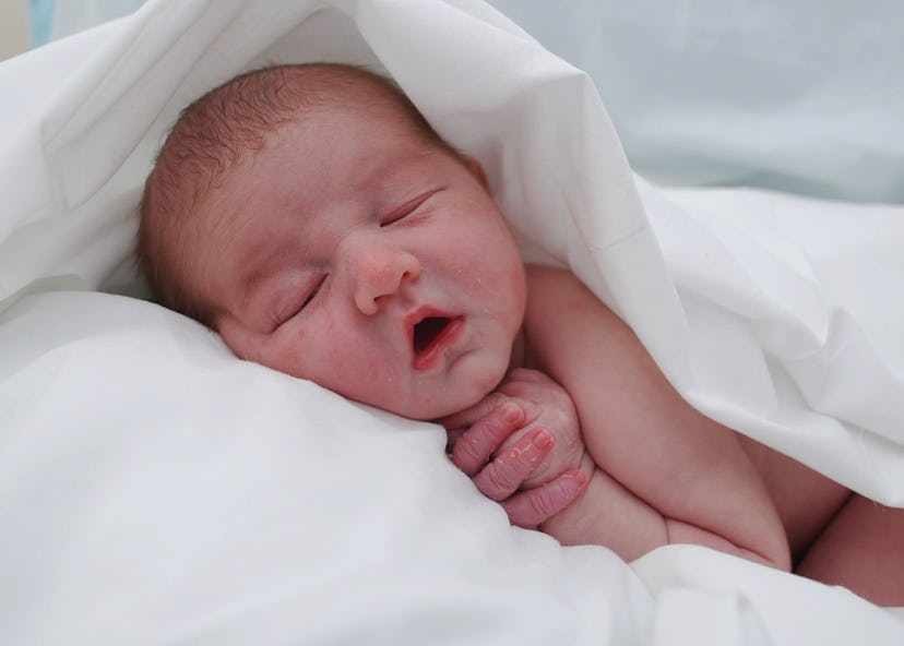 Newborn baby lying on white sheets